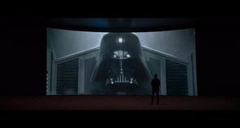 Movie still from “Obi-Wan Kenobi: A Jedi's Return” (2022), directed by David Gelb – A man standing in front of a large darth vader screen; Wide shot, Over the shoulder angle