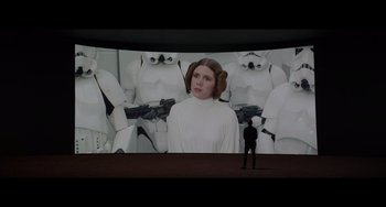 Movie still from “Obi-Wan Kenobi: A Jedi's Return” (2022), directed by David Gelb – A person standing in front of a large screen; Wide shot, Over the shoulder angle