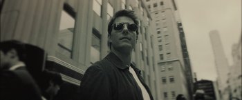Movie still from “Oblivion” (2013), directed by Joseph Kosinski – A man wearing sunglasses standing in front of a tall building; Close Up shot, Low angle