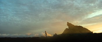 Movie still from “Oblivion” (2013), directed by Joseph Kosinski – A person standing on top of a hill at sunset; Extreme Wide shot, Low angle