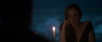 Movie still from “Oblivion” (2013), directed by Joseph Kosinski – A woman sitting in front of a lit candle in the dark; Close Up shot, Over the shoulder angle
