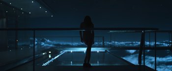 Movie still from “Oblivion” (2013), directed by Joseph Kosinski – A woman standing in front of a pool at night; Wide shot, Low angle