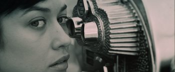 Movie still from “Oblivion” (2013), directed by Joseph Kosinski – A woman looking through a pair of eye glasses; Extreme Close Up shot, Low angle