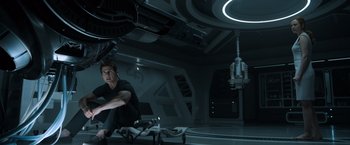 Movie still from “Oblivion” (2013), directed by Joseph Kosinski – A man sitting on top of a table in a room; Wide shot, High angle