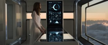 Movie still from “Oblivion” (2013), directed by Joseph Kosinski – A woman standing in front of a large display screen; Medium shot, Overhead angle