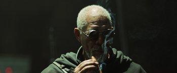 Movie still from “Oblivion” (2013), directed by Joseph Kosinski – An older man smoking a cigarette in a dimly - lit room; Close Up shot, Low angle