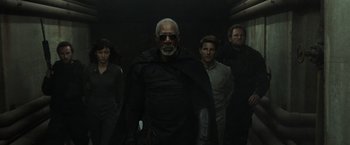 Movie still from “Oblivion” (2013), directed by Joseph Kosinski – A group of people standing next to each other in the dark; Medium shot, Over the shoulder angle