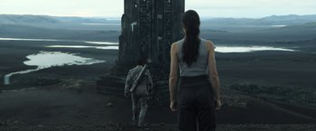 Movie still from “Oblivion” (2013), directed by Joseph Kosinski – A woman and a man standing in front of a tall tower; Wide shot, Low angle