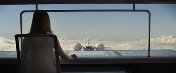 Movie still from “Oblivion” (2013), directed by Joseph Kosinski – A woman sitting in front of an airplane on a cloudy day; Wide shot, Low angle
