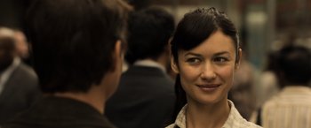 Movie still from “Oblivion” (2013), directed by Joseph Kosinski – A woman smiles at the camera as a man looks on; Close Up shot, Over the shoulder angle