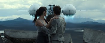 Movie still from “Oblivion” (2013), directed by Joseph Kosinski – A man and a woman standing next to each other in front of an airplane; Wide shot, Low angle