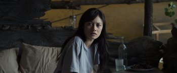 Movie still from “Oblivion” (2013), directed by Joseph Kosinski – A woman sitting at a table with a bottle of alcohol; Close Up shot, Over the shoulder angle