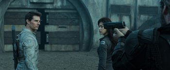 Movie still from “Oblivion” (2013), directed by Joseph Kosinski – A person holding a gun up to their face; Medium shot, Over the shoulder angle