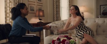 Movie still from “Ocean's Eight” (2018), directed by Gary Ross – A woman sitting at a table with a vase of flowers; Medium shot, Over the shoulder angle