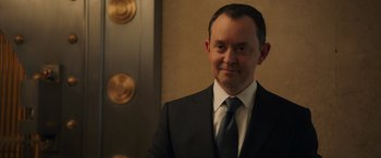 Movie still from “Ocean's Eight” (2018), directed by Gary Ross – A person wearing a suit and tie; Close Up shot, Over the shoulder angle