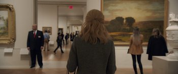 Movie still from “Ocean's Eight” (2018), directed by Gary Ross – A woman is standing in front of a painting in an art gallery; Medium shot, Over the shoulder angle
