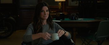 Movie still from “Ocean's Eight” (2018), directed by Gary Ross – A woman sitting in a chair holding a cup; Medium shot, High angle