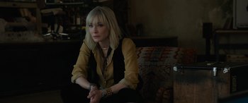 Movie still from “Ocean's Eight” (2018), directed by Gary Ross – A woman sitting on top of a couch in front of a window; Medium shot, Over the shoulder angle