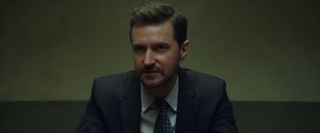 Movie still from “Ocean's Eight” (2018), directed by Gary Ross – A person wearing a suit and tie; Close Up shot, Over the shoulder angle