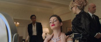 Movie still from “Ocean's Eight” (2018), directed by Gary Ross – A woman is putting a necklace on her neck in front of another woman; Medium shot, Over the shoulder angle