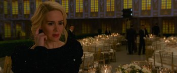 Movie still from “Ocean's Eight” (2018), directed by Gary Ross – A woman standing in front of a room filled with tables and chairs; Close Up shot, Over the shoulder angle
