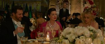 Movie still from “Ocean's Eight” (2018), directed by Gary Ross – A woman sitting at a dinner table wearing a necklace; Medium shot, Over the shoulder angle