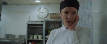 Movie still from “Ocean's Eight” (2018), directed by Gary Ross – A woman in a chef's outfit in front of a wall clock; Close Up shot, Low angle