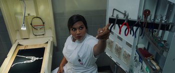 Movie still from “Ocean's Eight” (2018), directed by Gary Ross – A woman in a white lab coat holding a pair of scissors; Medium shot, Overhead angle