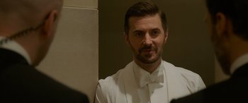 Movie still from “Ocean's Eight” (2018), directed by Gary Ross – A man in a white shirt and bow tie looking into a mirror; Close Up shot, Over the shoulder angle