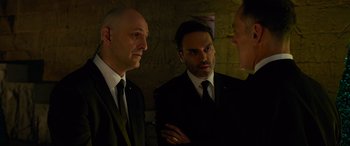 Movie still from “Ocean's Eight” (2018), directed by Gary Ross – A group of men standing next to each other in a room; Medium shot, Over the shoulder angle