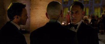 Movie still from “Ocean's Eight” (2018), directed by Gary Ross – A man in a suit and tie standing next to another man in a suit and tie; Close Up shot, Over the shoulder angle