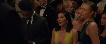 Movie still from “Ocean's Eight” (2018), directed by Gary Ross – A woman in a yellow dress in front of a group of people; Close Up shot, Over the shoulder angle