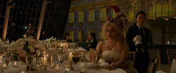 Movie still from “Ocean's Eight” (2018), directed by Gary Ross – A woman sitting at a table with a lot of wine; Medium shot, Over the shoulder angle