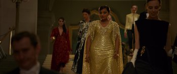 Movie still from “Ocean's Eight” (2018), directed by Gary Ross – A group of women walking down a runway wearing gold dresses; Medium shot, Over the shoulder angle