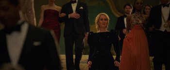 Movie still from “Ocean's Eight” (2018), directed by Gary Ross – A group of people in formal wear standing in a room; Medium shot, Over the shoulder angle