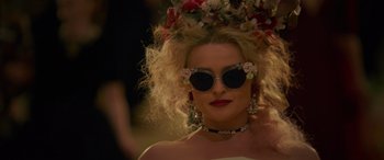 Movie still from “Ocean's Eight” (2018), directed by Gary Ross – A person wearing sunglasses and a floral headpiece; Close Up shot, Over the shoulder angle