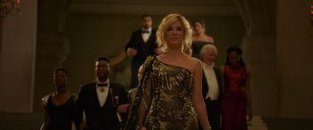 Movie still from “Ocean's Eight” (2018), directed by Gary Ross – A woman in a gold dress standing in front of a group of people; Medium shot, Low angle