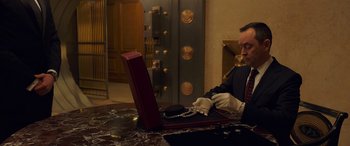 Movie still from “Ocean's Eight” (2018), directed by Gary Ross – A man sitting at a table looking at a laptop computer; Medium shot, High angle