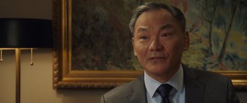 Movie still from “Ocean's Eight” (2018), directed by Gary Ross – An older man in a gray suit and a blue tie; Close Up shot, Over the shoulder angle