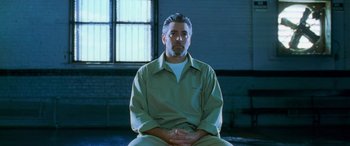 Movie still from “Ocean's Eleven” (2001), directed by Steven Soderbergh – A man sitting in a chair in front of a window; Medium shot, Low angle