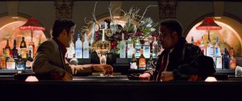 Movie still from “Ocean's Eleven” (2001), directed by Steven Soderbergh – Two men sitting at a bar drinking and talking to each other; Medium shot, Over the shoulder angle