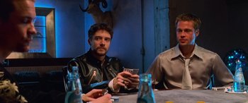 Movie still from “Ocean's Eleven” (2001), directed by Steven Soderbergh – A man sitting at a table holding a pack of cards; Medium shot, Low angle