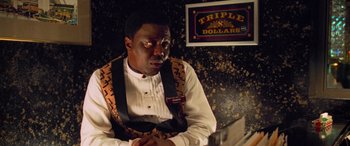 Movie still from “Ocean's Eleven” (2001), directed by Steven Soderbergh – A man sitting in front of a sign in front of a wall; Close Up shot, Over the shoulder angle