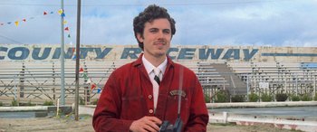Movie still from “Ocean's Eleven” (2001), directed by Steven Soderbergh – A man in a red jacket holding a gun in front of a stadium; Close Up shot, Low angle