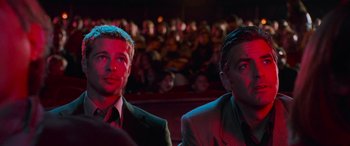 Movie still from “Ocean's Eleven” (2001), directed by Steven Soderbergh – A couple of men sitting next to each other in front of a crowd; Medium shot, Low angle