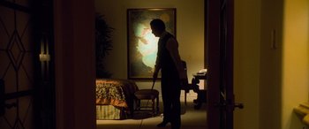 Movie still from “Ocean's Eleven” (2001), directed by Steven Soderbergh – A man standing in a living room holding a cane; Wide shot, Over the shoulder angle