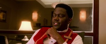 Movie still from “Ocean's Eleven” (2001), directed by Steven Soderbergh – A man in a red and white vest is looking at his chin; Close Up shot, High angle