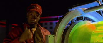Movie still from “Ocean's Eleven” (2001), directed by Steven Soderbergh – A man wearing a red hat standing in front of a large green object; Close Up shot, Low angle