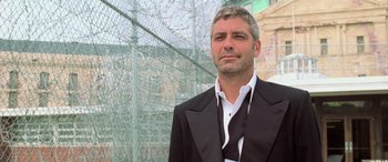 Movie still from “Ocean's Eleven” (2001), directed by Steven Soderbergh – A man wearing a suit and tie standing in front of a fence; Close Up shot, Low angle