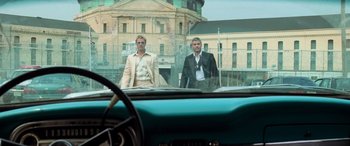 Movie still from “Ocean's Eleven” (2001), directed by Steven Soderbergh – A couple of men standing next to each other in front of a car; Wide shot, Low angle